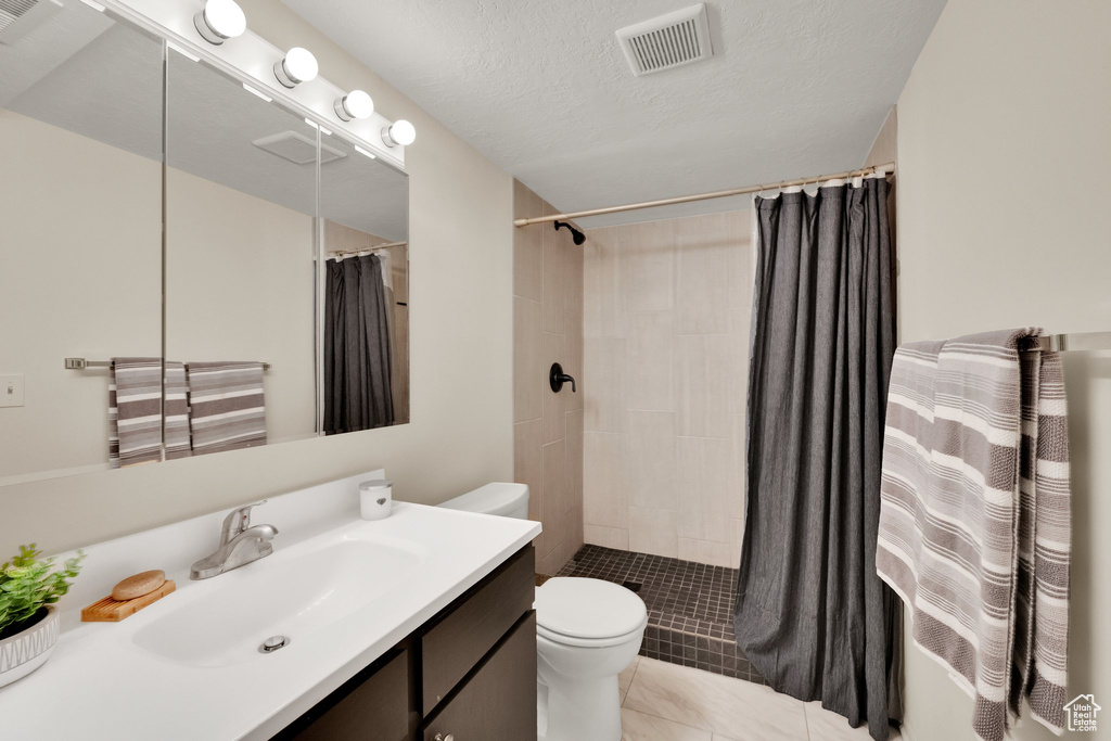 Bathroom featuring vanity, tiled shower, and tile patterned flooring