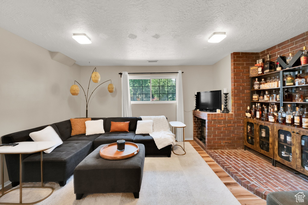 Living room with wood finished floors, a fireplace, and a textured ceiling