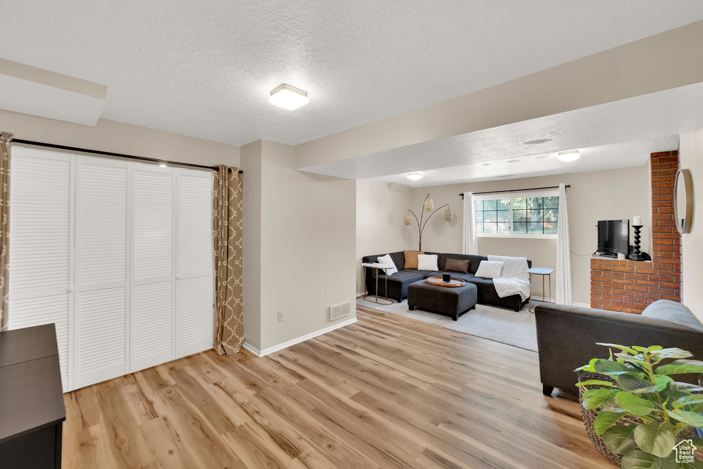 Living area featuring light wood-type flooring and a textured ceiling