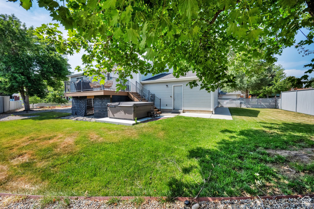 Fenced backyard with a hot tub, a deck, a patio, and stairs