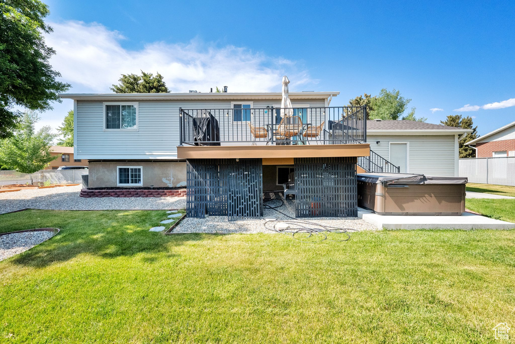Rear view of property with a hot tub, a patio, and a deck