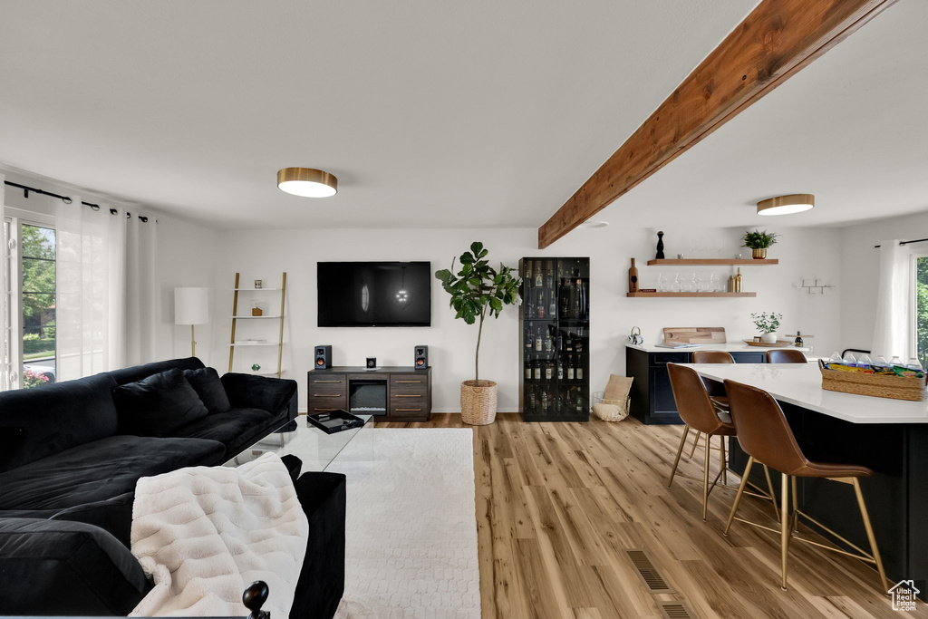 Living area with light wood-style floors and beamed ceiling
