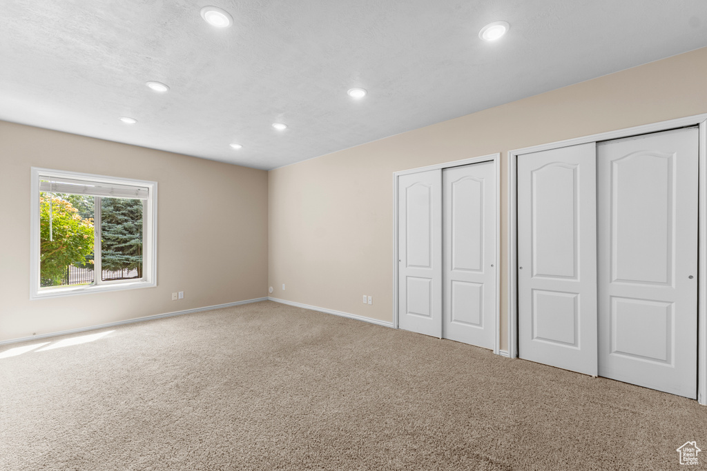 Unfurnished bedroom featuring recessed lighting, carpet, and two closets