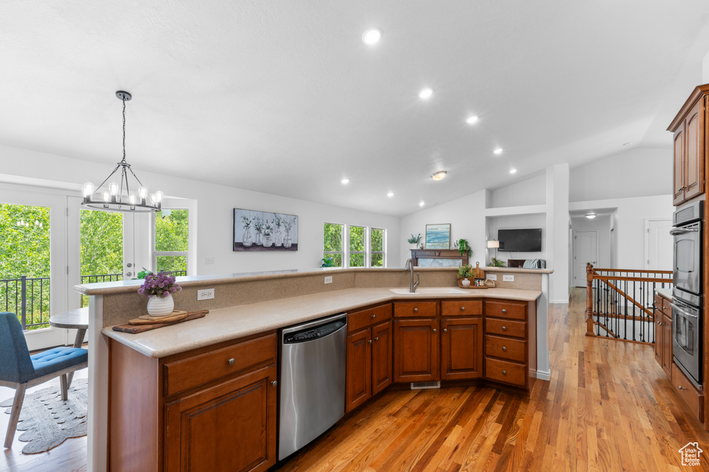 Kitchen with stainless steel appliances, light countertops, light wood-type flooring, lofted ceiling, and recessed lighting