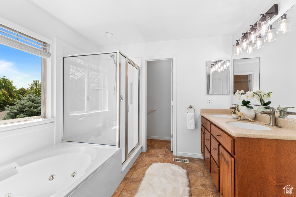 Full bath with a stall shower, double vanity, plenty of natural light, and a jetted tub