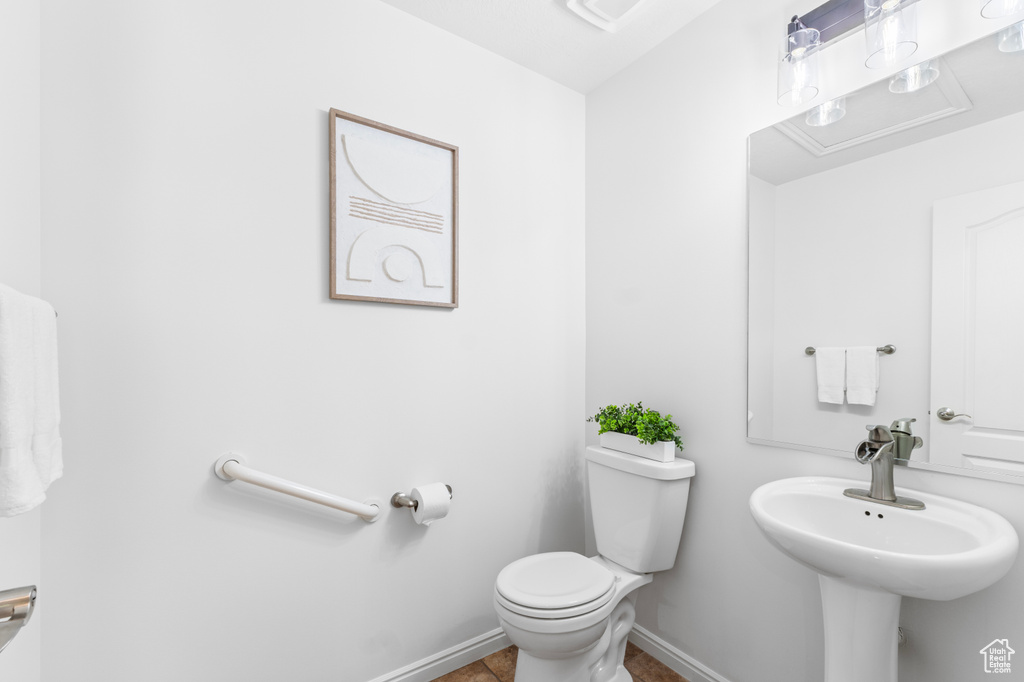 Half bathroom with toilet and tile patterned flooring