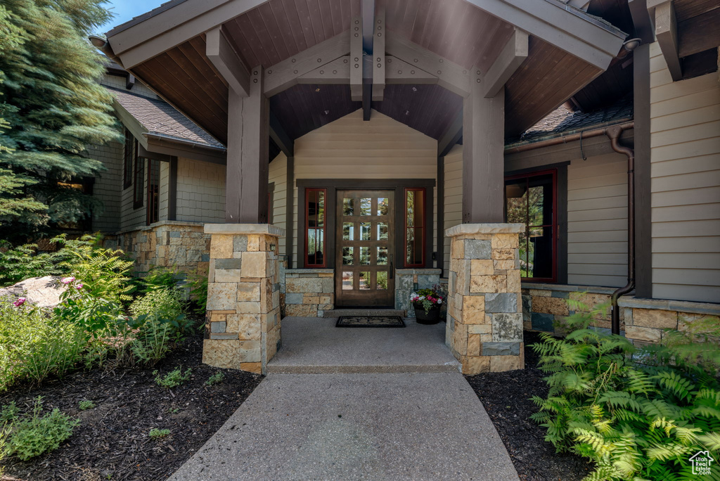 Entrance to property featuring stone siding, covered porch, and french doors