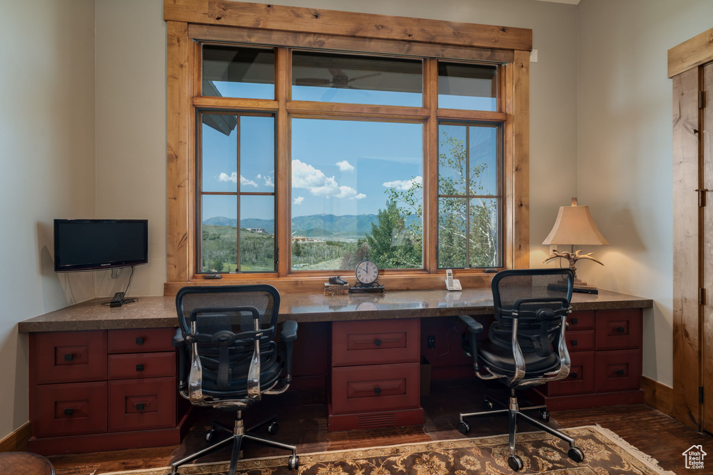 Home office featuring built in study area, healthy amount of natural light, and dark wood finished floors