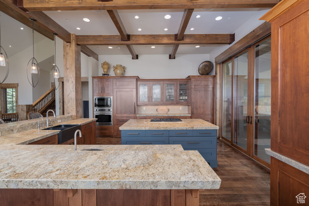 Kitchen featuring appliances with stainless steel finishes, a large island with sink, dark wood-style flooring, recessed lighting, and beam ceiling