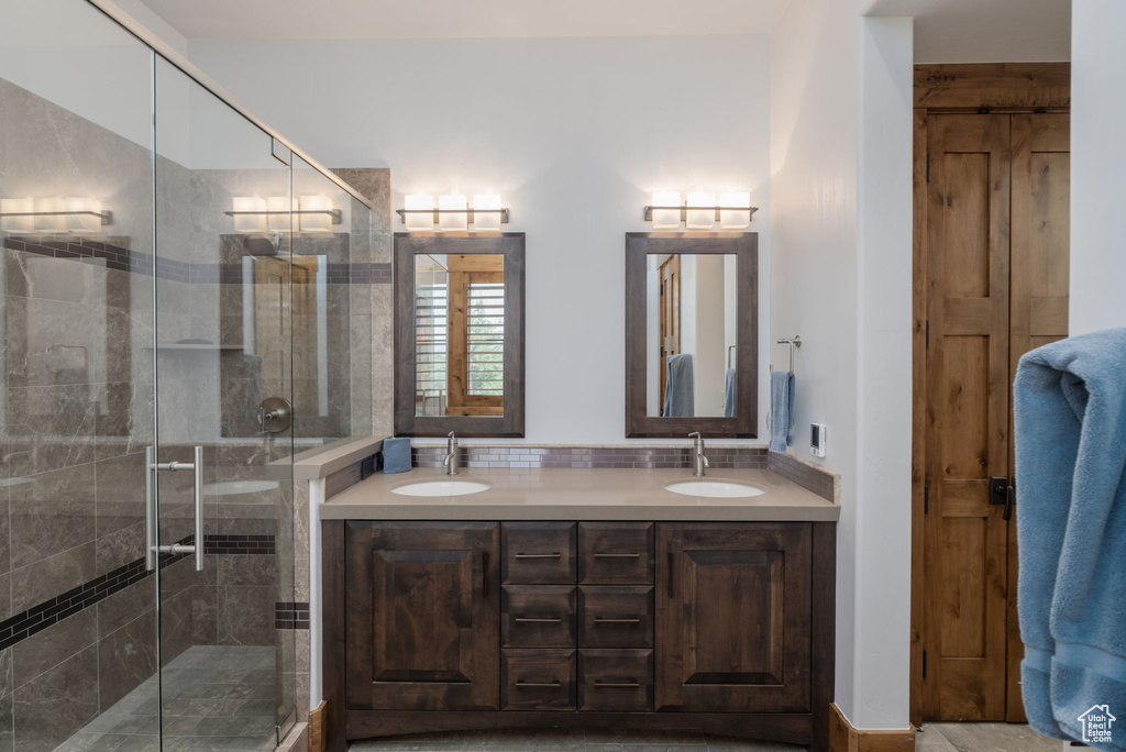 Full bath with double vanity and a shower stall