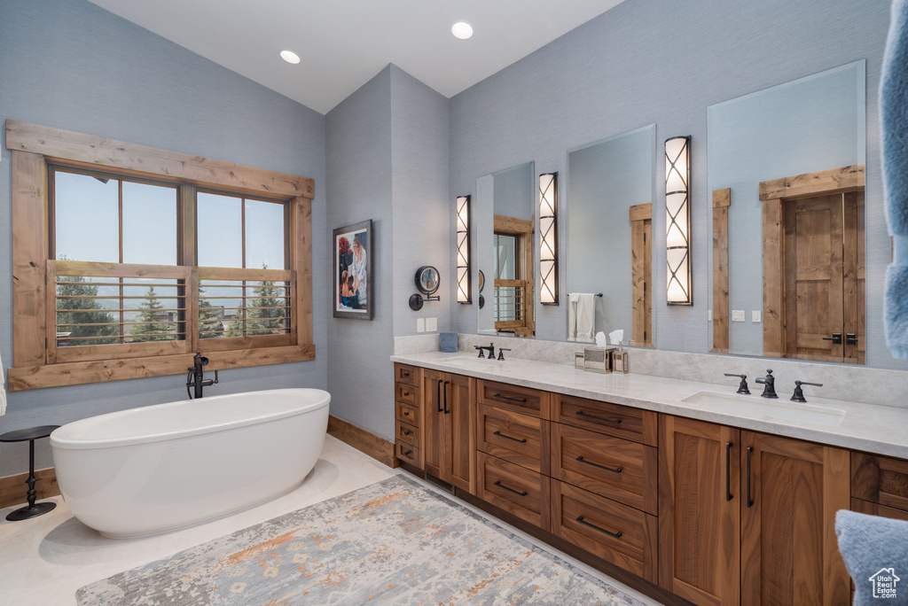 Full bath with double vanity, a soaking tub, and lofted ceiling