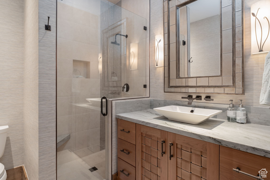 Full bath featuring vanity, a shower stall, and tile walls