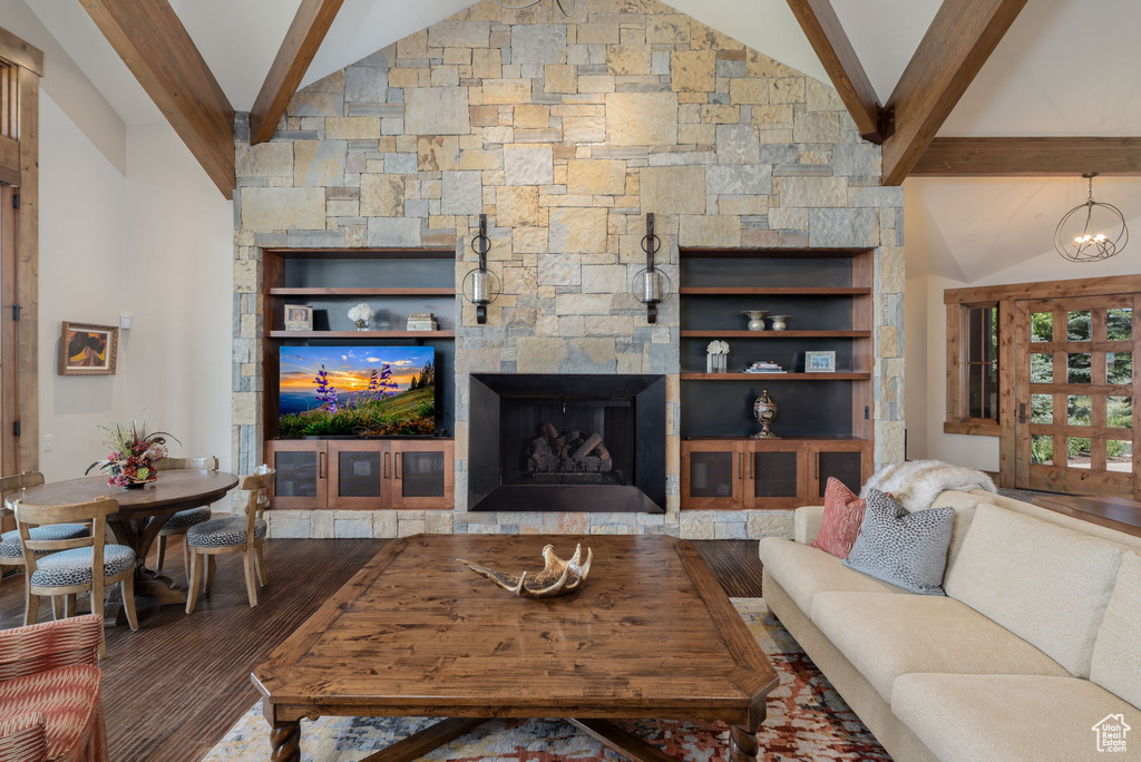 Living area featuring wood finished floors, beam ceiling, high vaulted ceiling, a stone fireplace, and built in features