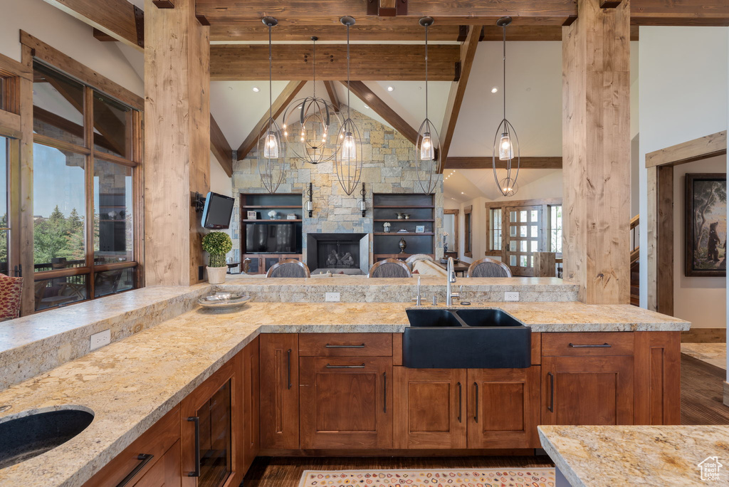 Kitchen with brown cabinets, light stone counters, open floor plan, and hanging light fixtures