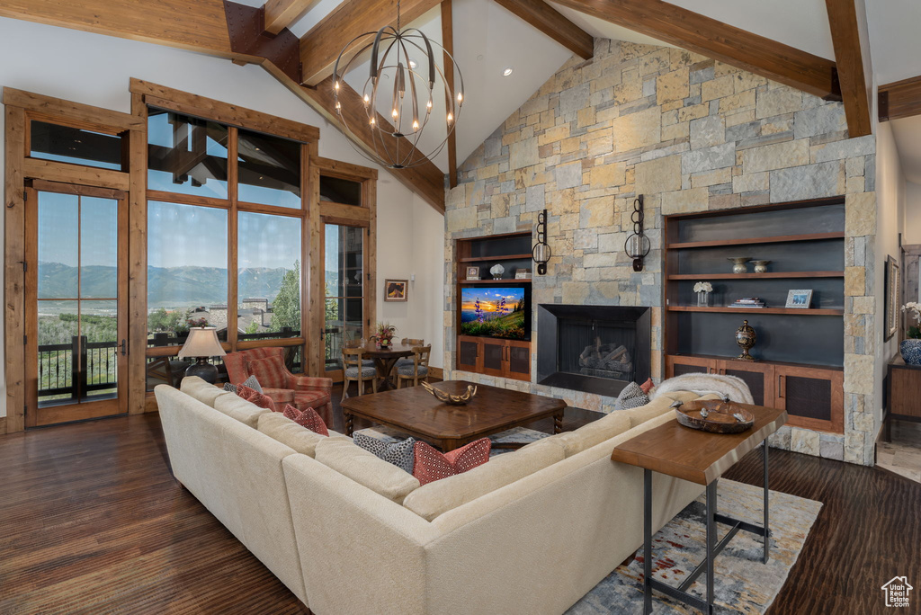 Living room with beam ceiling, a fireplace, a chandelier, wood finished floors, and high vaulted ceiling