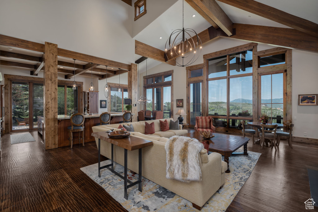 Living area featuring beam ceiling, a high ceiling, a chandelier, dark wood-type flooring, and recessed lighting