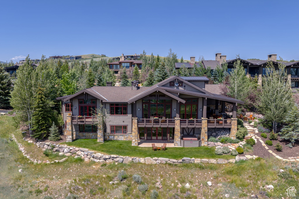 Rear view of property with stone siding, a yard, and a patio area