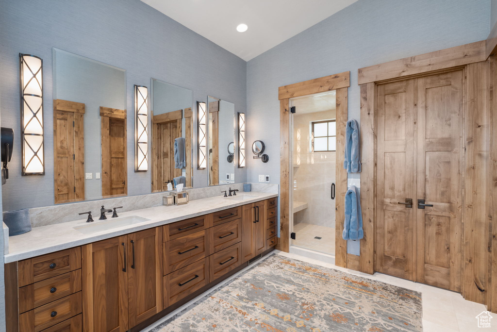 Full bath with double vanity, a stall shower, and lofted ceiling