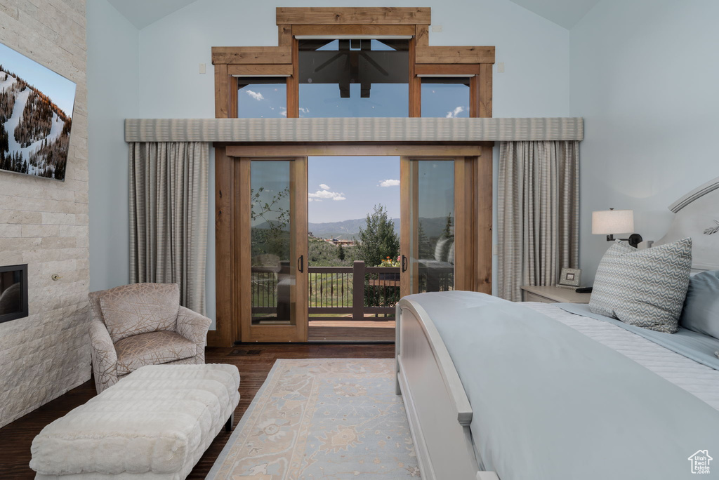 Bedroom with access to exterior, wood finished floors, a glass covered fireplace, a mountain view, and high vaulted ceiling