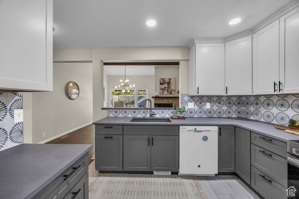 Kitchen featuring white dishwasher, gray cabinetry, backsplash, a chandelier, and recessed lighting