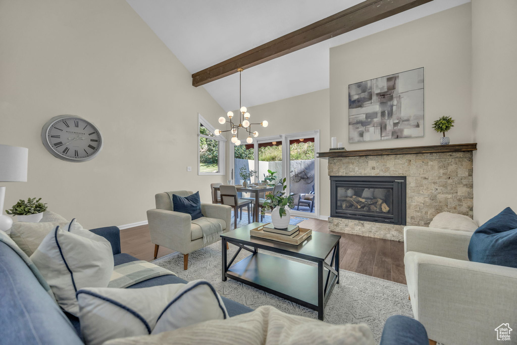 Living room with high vaulted ceiling, wood finished floors, a chandelier, a glass covered fireplace, and beam ceiling