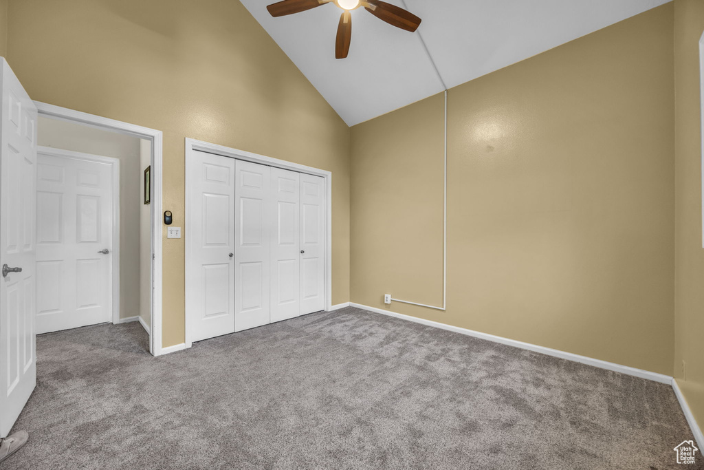 Unfurnished bedroom with carpet floors, high vaulted ceiling, a closet, and ceiling fan