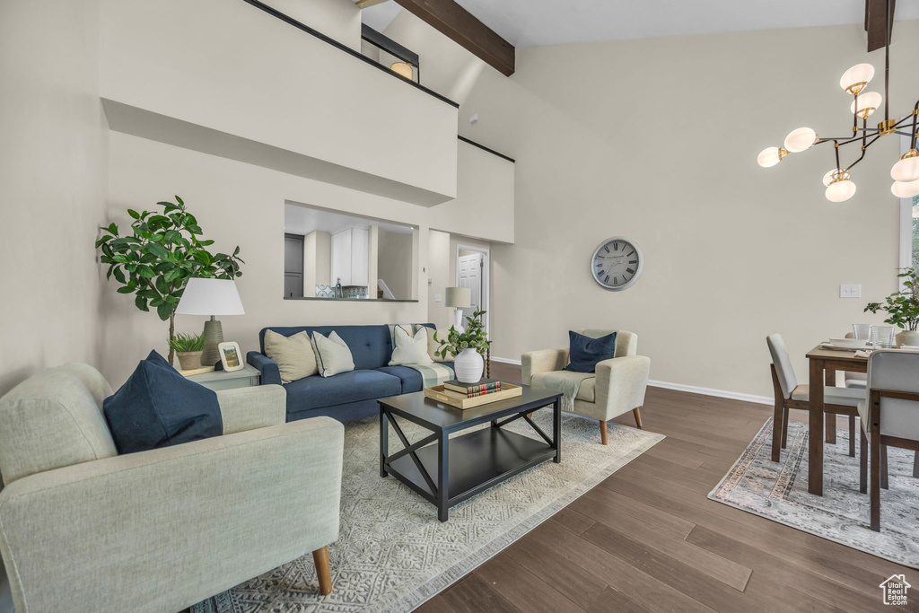 Living area with beamed ceiling, a chandelier, wood finished floors, and high vaulted ceiling