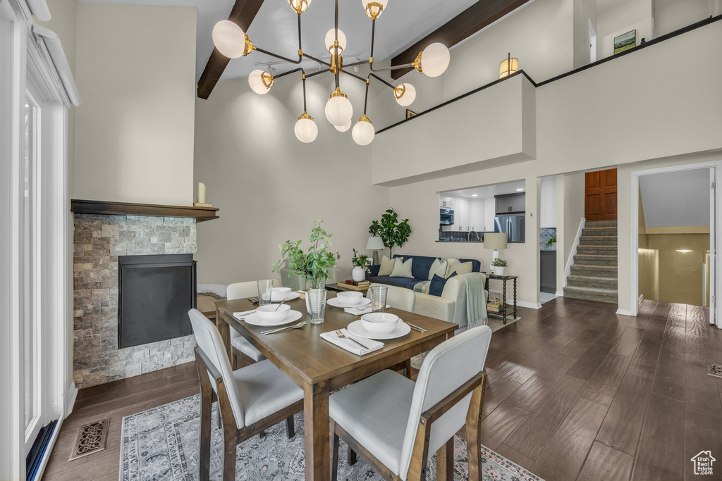 Dining area featuring a fireplace, stairs, wood finished floors, a towering ceiling, and a chandelier