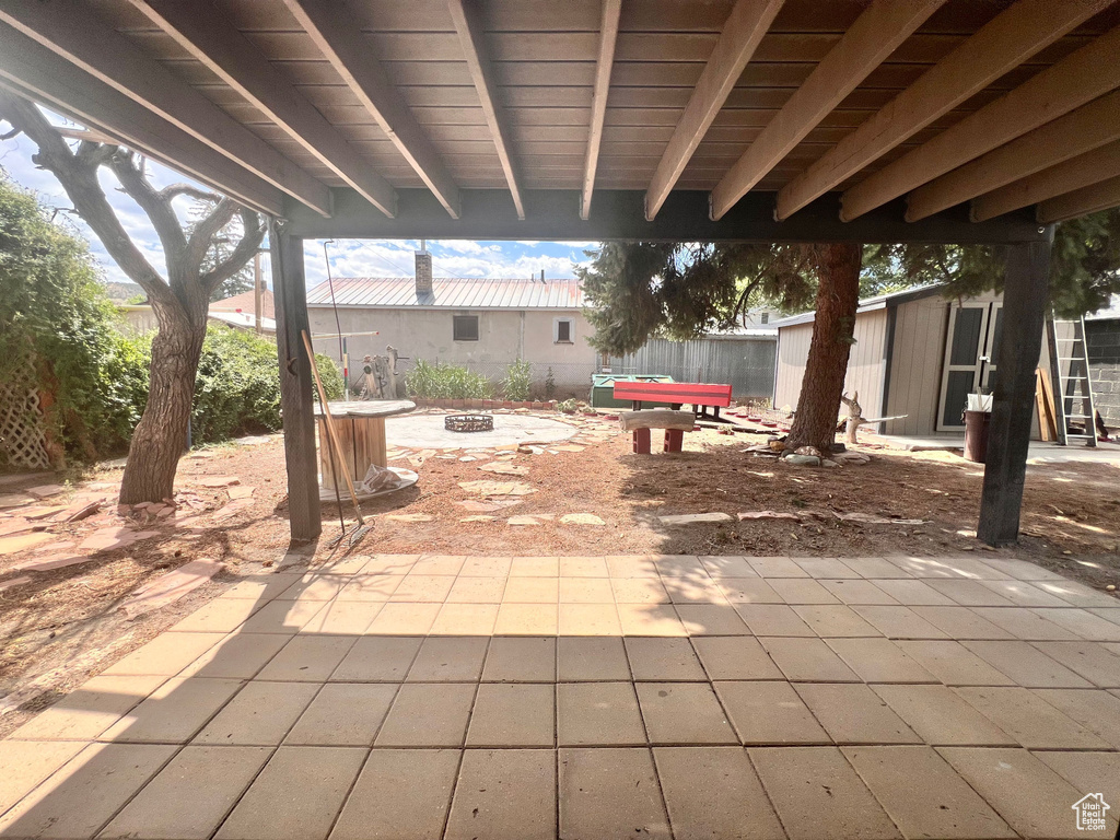 View of patio featuring a fire pit and a storage unit