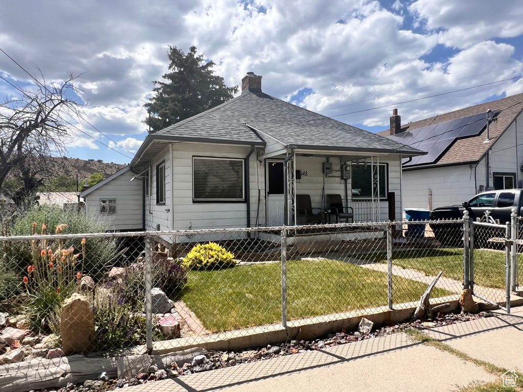 View of front of house with a fenced front yard, a porch, a chimney, a shingled roof, and a gate