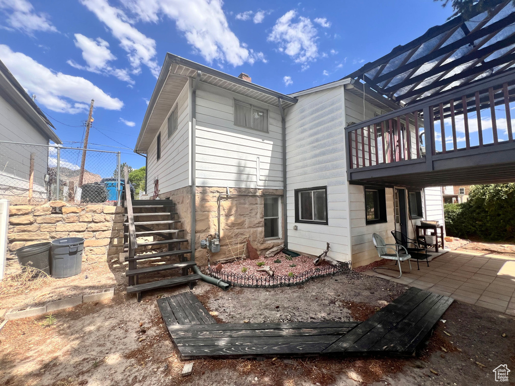 Rear view of house with a patio, stairway, and a chimney