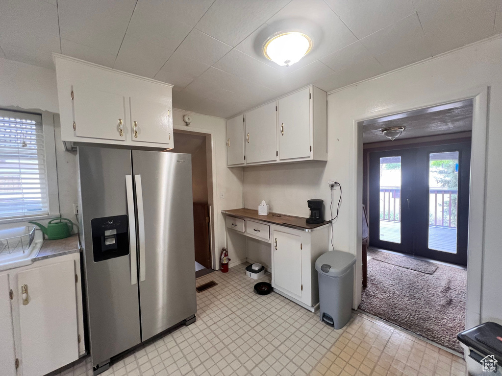 Kitchen featuring stainless steel fridge with ice dispenser, white cabinetry, and french doors