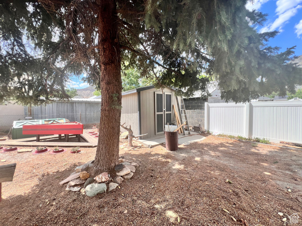Fenced backyard featuring a shed