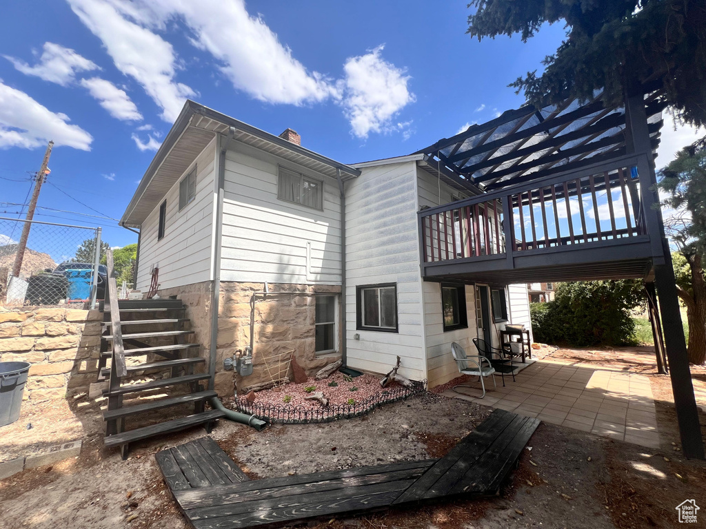 Rear view of house with a patio area, a chimney, and stairway