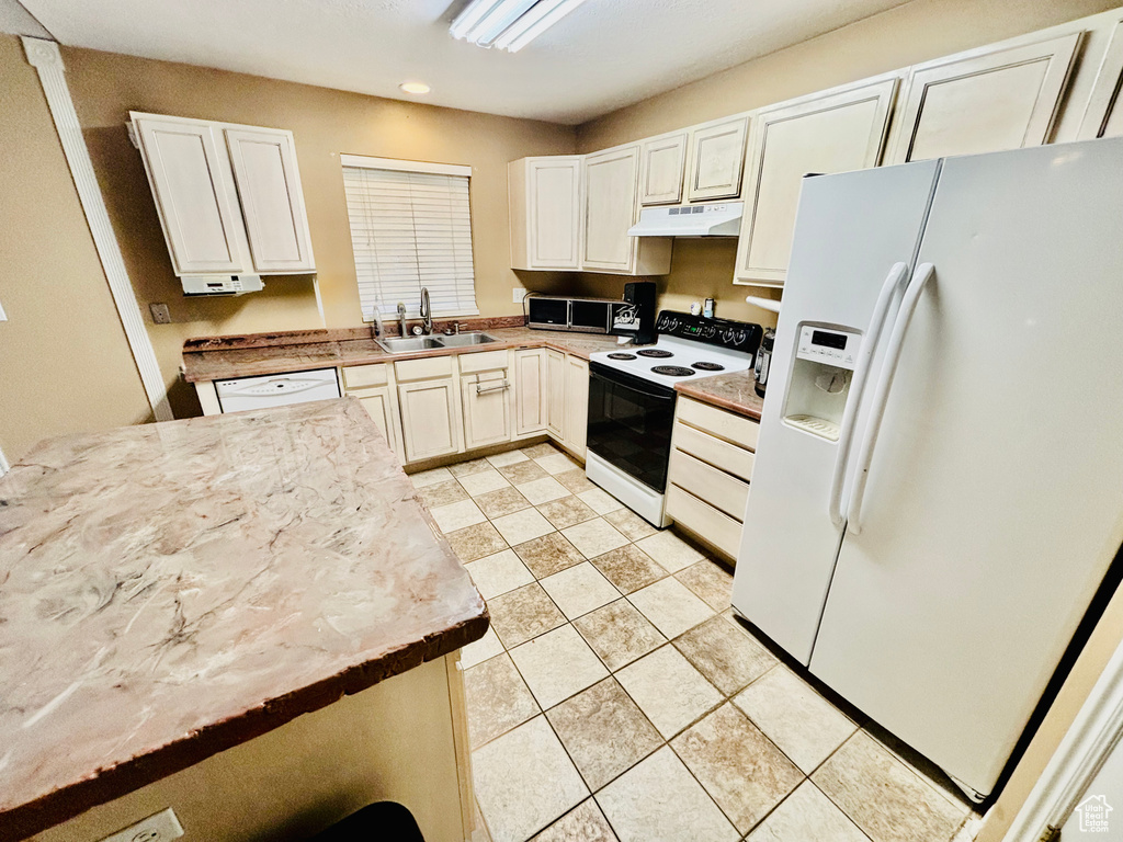 Kitchen featuring white appliances, under cabinet range hood, white cabinets, recessed lighting, and light countertops