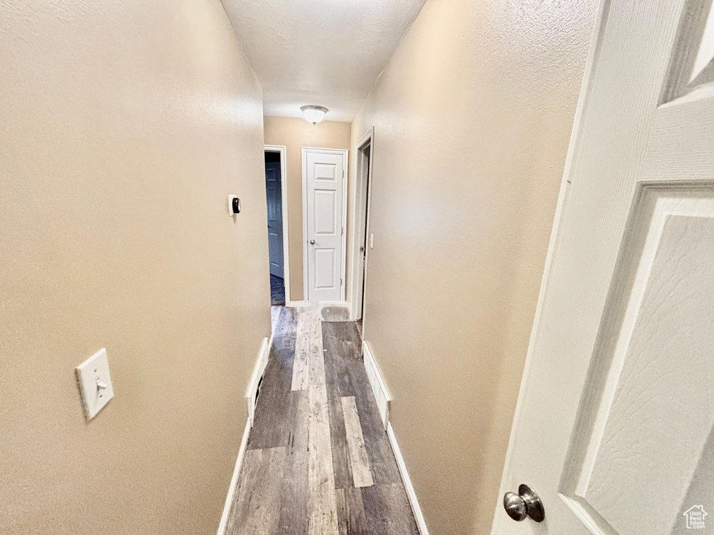 Hallway featuring dark wood-style floors and baseboards
