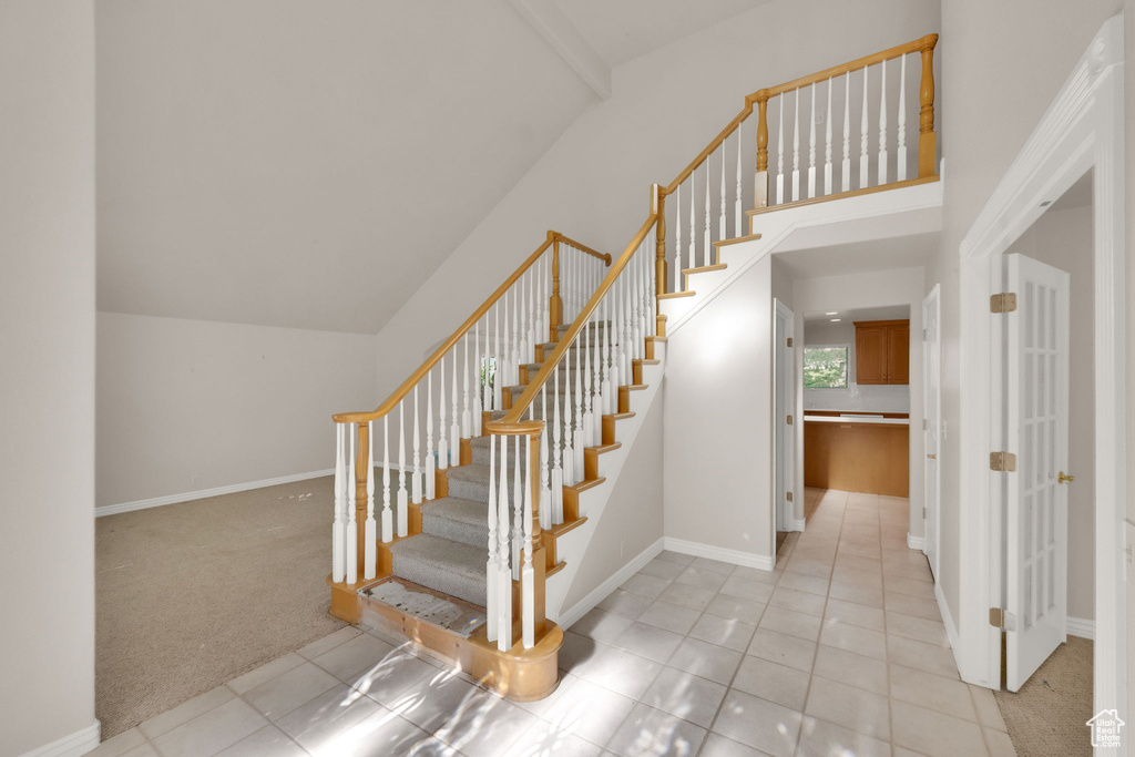 Stairway featuring vaulted ceiling, carpet flooring, and tile patterned flooring