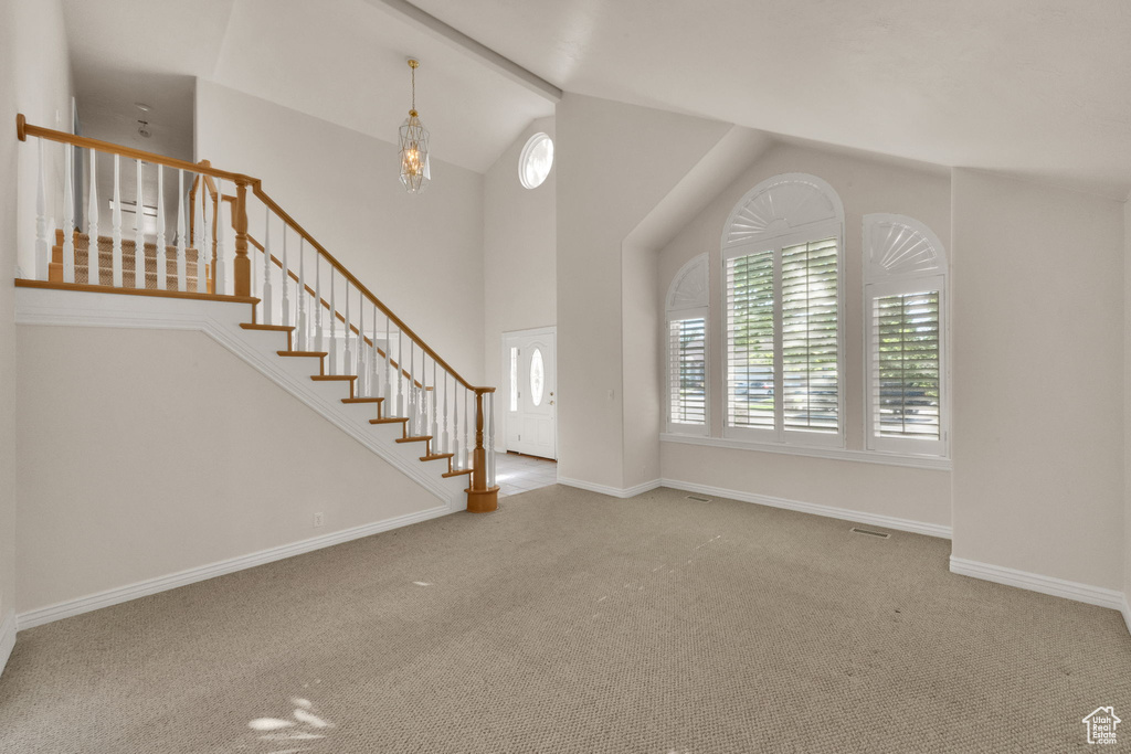 Carpeted entryway with vaulted ceiling and stairs