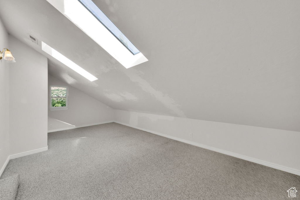 Bonus room featuring a skylight, lofted ceiling, and carpet floors