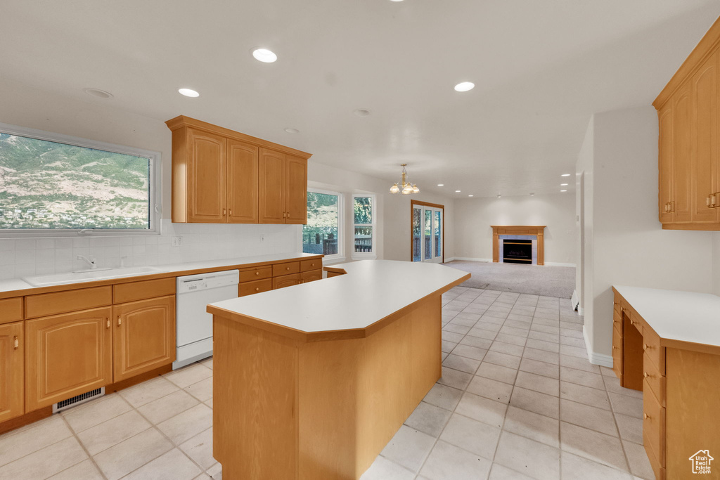Kitchen with white dishwasher, a kitchen island, light countertops, recessed lighting, and a chandelier