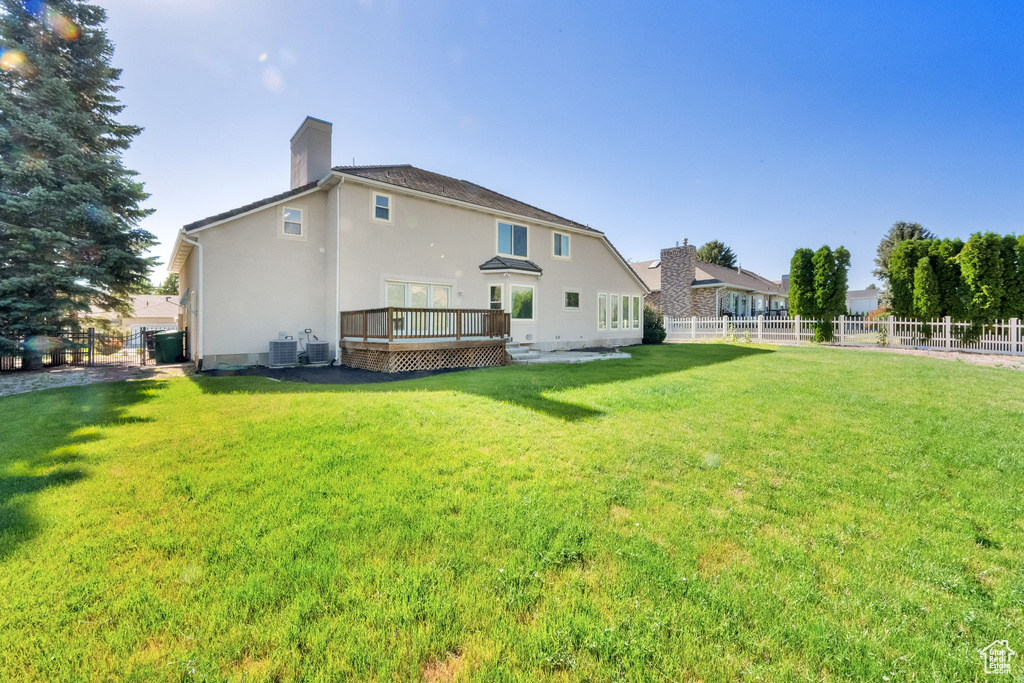 Back of house featuring a fenced backyard, a deck, a chimney, and stucco siding