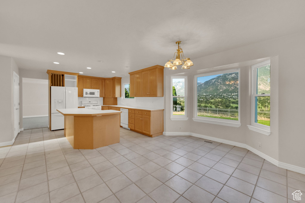 Kitchen with white appliances, light countertops, light tile patterned floors, a center island, and a chandelier