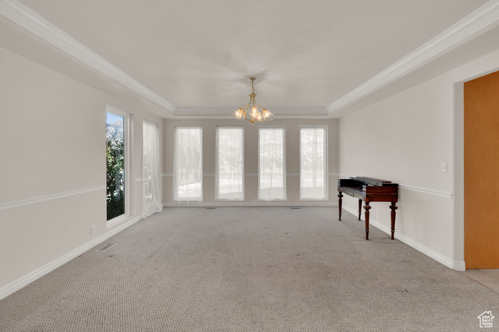 Unfurnished room with a chandelier, carpet, a tray ceiling, and crown molding