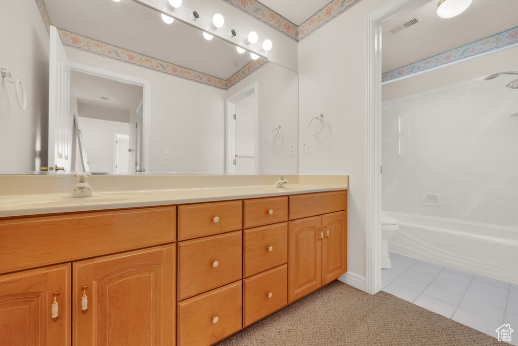 Full bathroom featuring double vanity, tile patterned floors, and shower / washtub combination