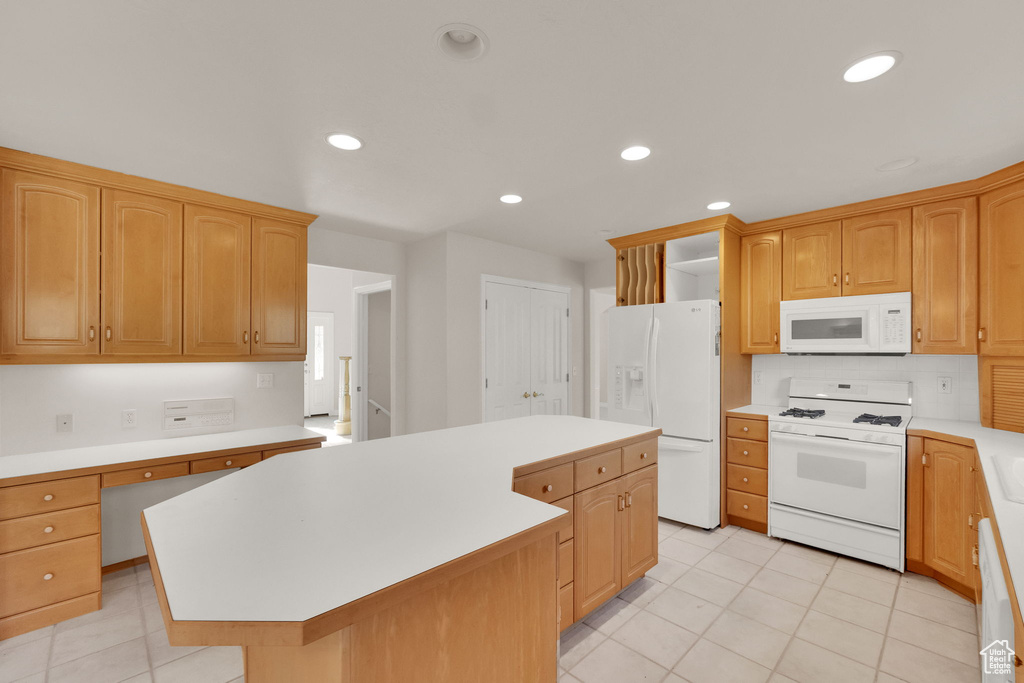 Kitchen with white appliances, a kitchen island, light countertops, light tile patterned flooring, and recessed lighting