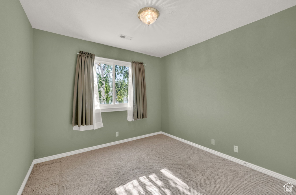 Carpeted spare room featuring baseboards