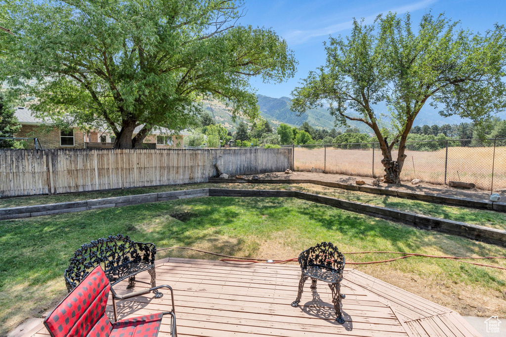 Wooden deck featuring a fenced backyard and a mountain view