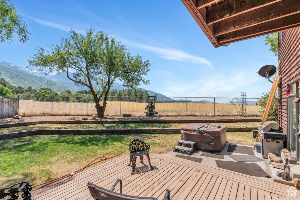 Wooden terrace with a fenced backyard, a mountain view, grilling area, and a rural view