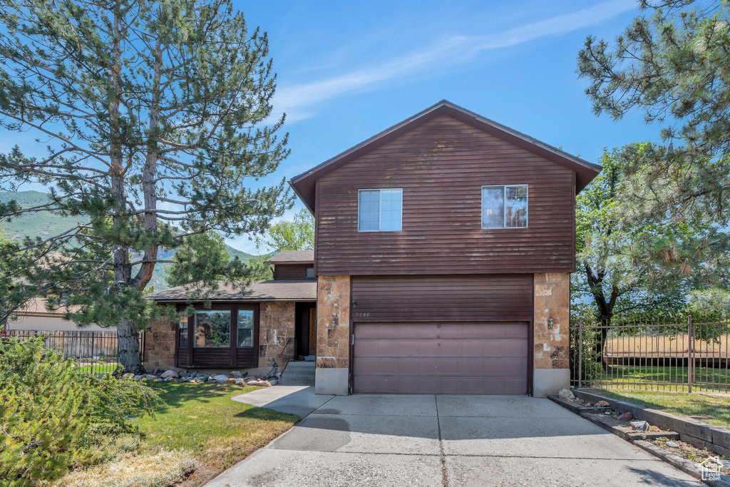 View of front of home featuring an attached garage, concrete driveway, and stone siding