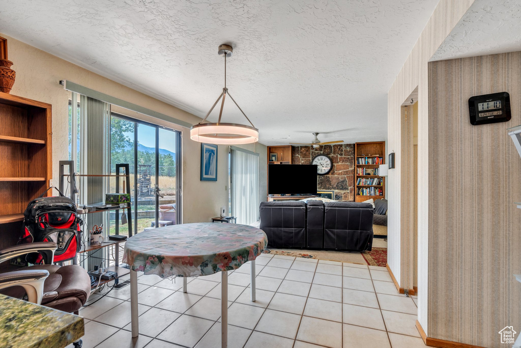 Dining room with a textured ceiling, light tile patterned floors, built in features, and a ceiling fan